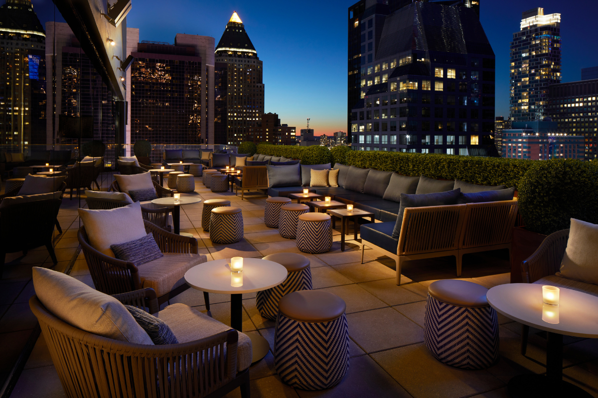 a rooftop patio with tables and chairs and a city skyline